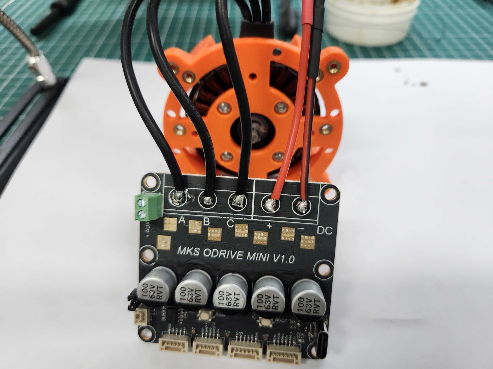 XDrive MINI driver board with the terminal blocks removed. Three black motor phase wires are soldered to pads A, B, and C, and red and black power wires to DC plus and minus.